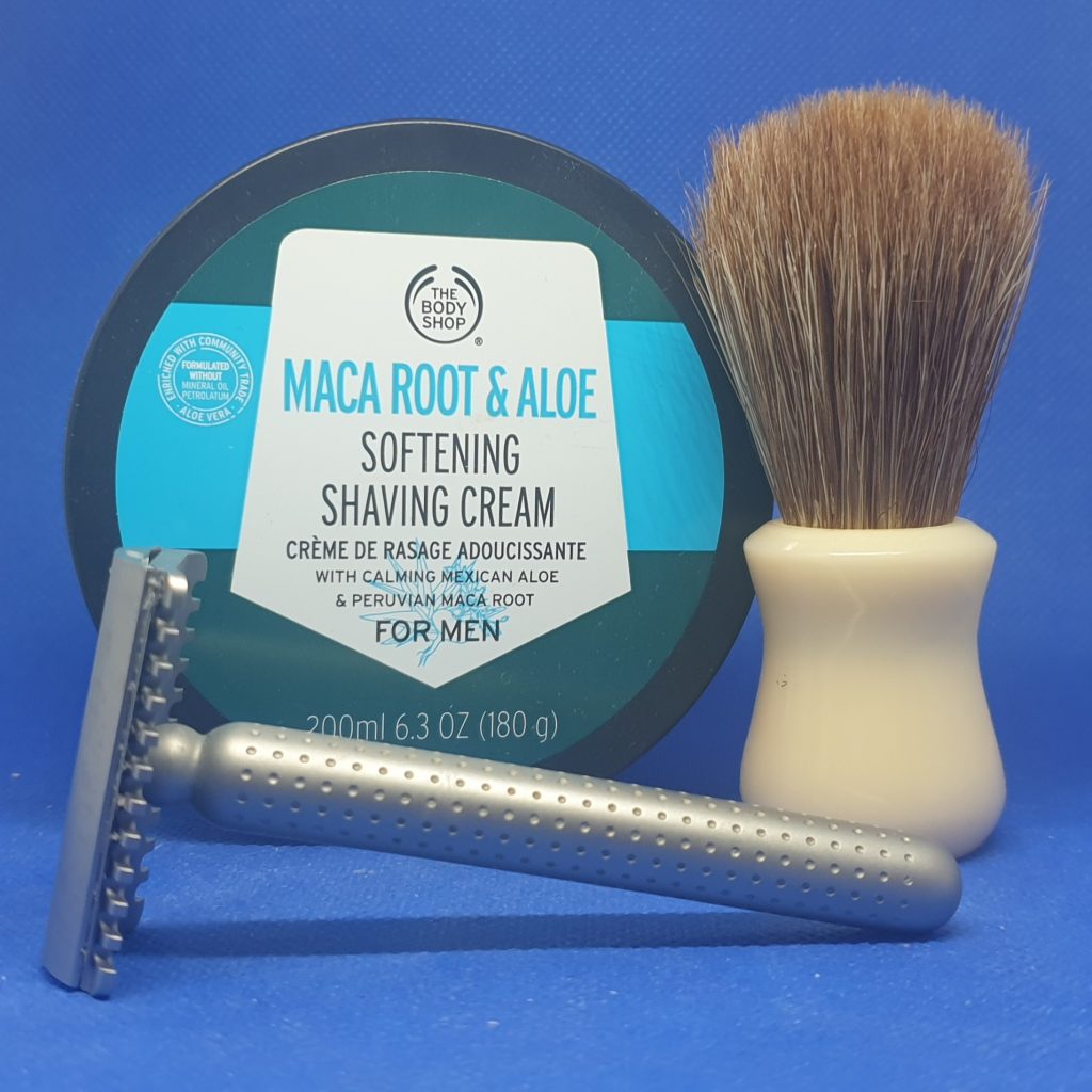 SOTD 2023 07 05 Against blue background; in front a Tatara razor, behind it to the right a Vie Long tan horse hair brush, to the left of that a dark green tub of Body Shop shaving cream